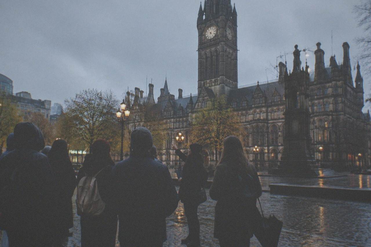 A group of visitors listening to a guide at the end of a free walking tour in Manchester city centre